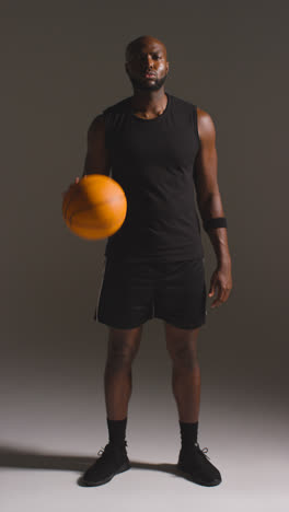 Vertical-Video-Full-Length-Studio-Vertical-Video-Portrait-Of-Male-Basketball-Player-Dribbling-And-Bouncing-Ball-Against-Grey-Background